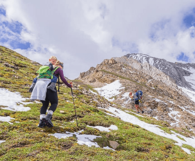 Two Parents Hiking With Children In The Mountains