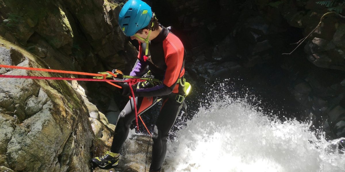 A man at the top of a waterfall attached to ropes while canyoning in Vancouver