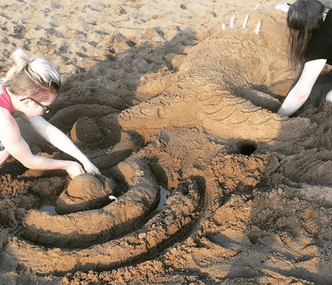 Two people creating sand sculptures at the beach