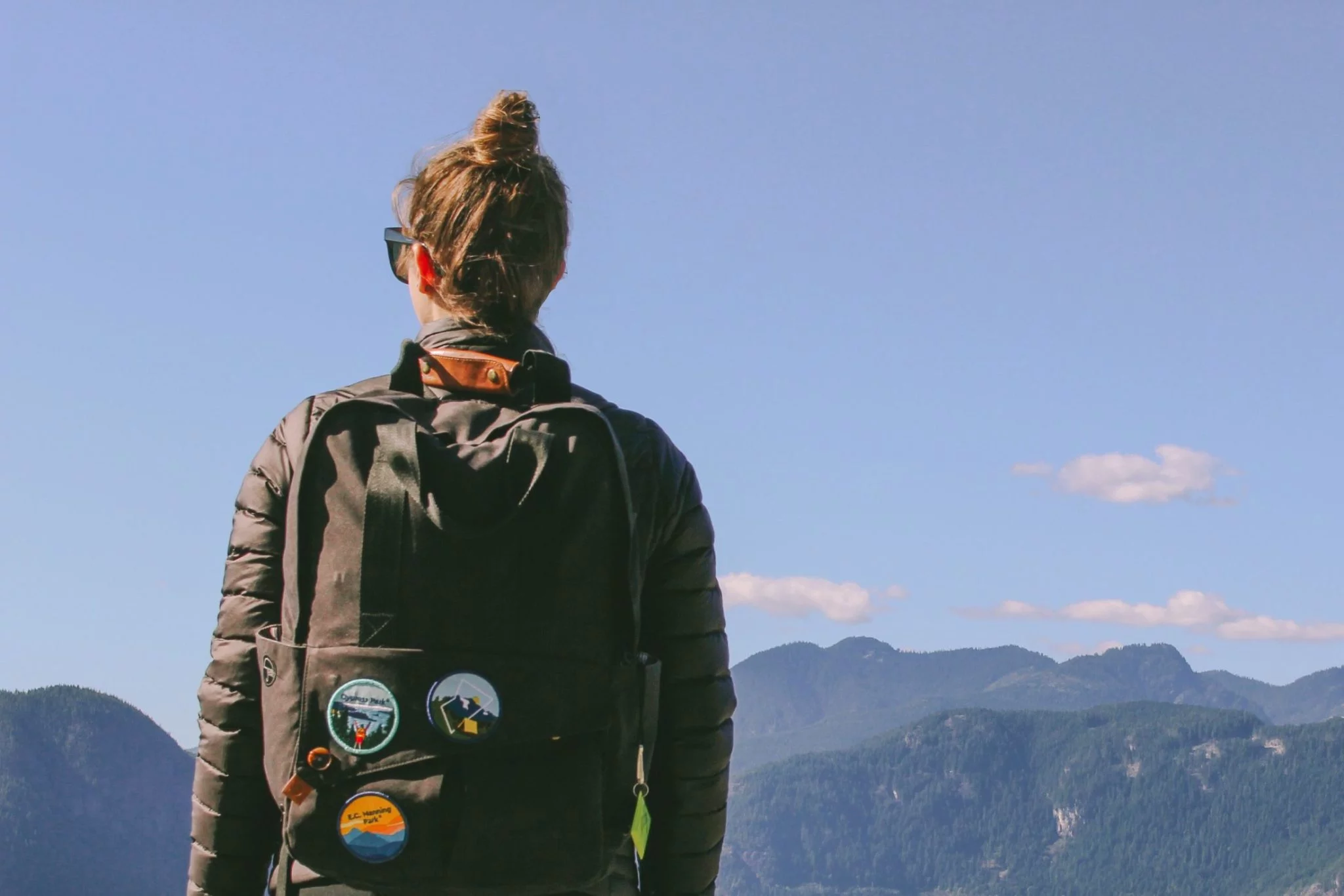 A girl with her back to the camera, wearing a backpack covered in BC Parks Foundation patches