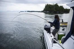 Woman Fishing On The Ocean Off A Boat In British Columbia