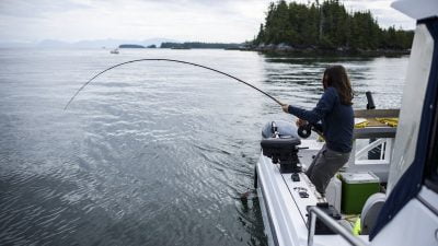 Woman Fishing On The Ocean Off A Boat In British Columbia