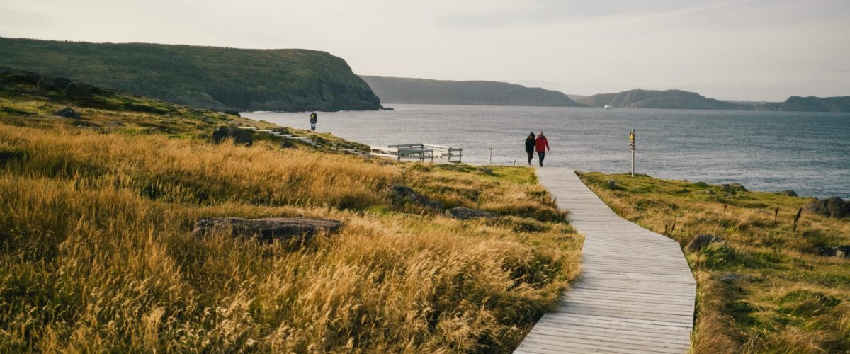 Image of people walking down a boardwalk leading to the ocean on Fogo Island, Newfoundland