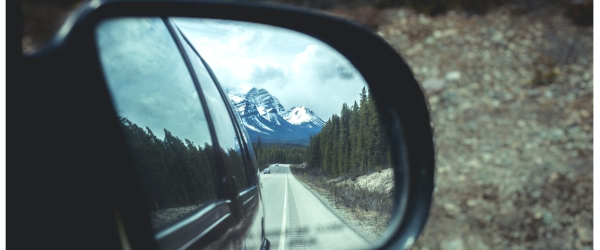 Rear view mirror showing Banff and the Canadian Rockies on a road trip