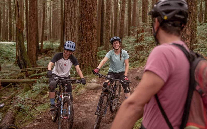 Two women with bikes and a guide teaching them how to mountain bike on an outdoor adventure
